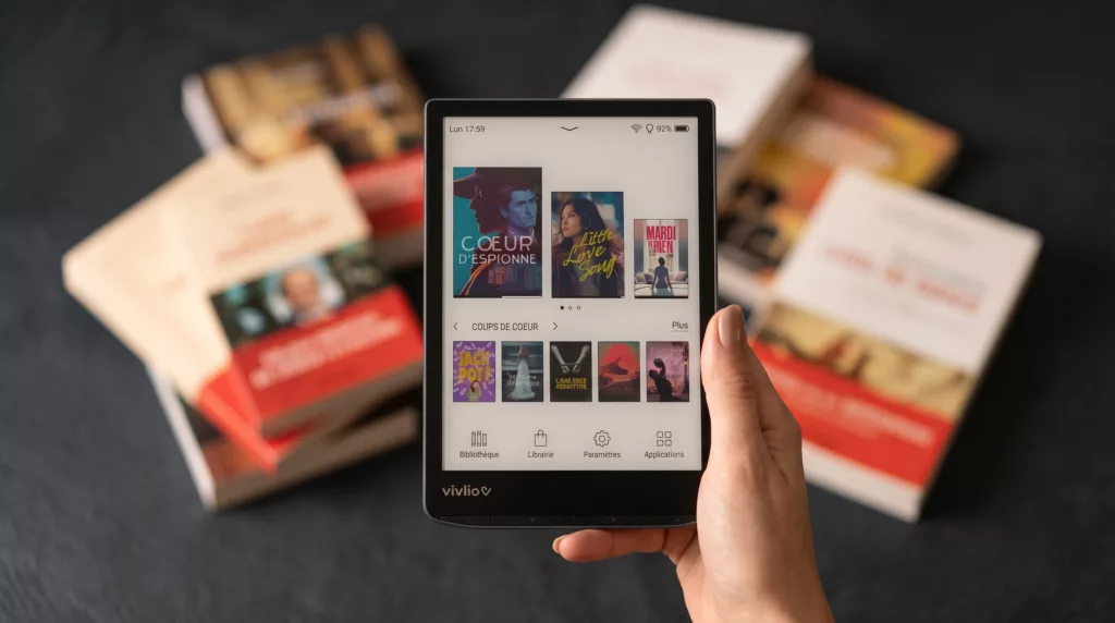 Une liseuse Vivlio devant une pile de livres papier