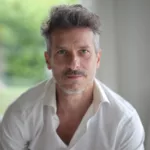 Portrait of an adult male with a quiff and blue eyes under the lights with a blurry background